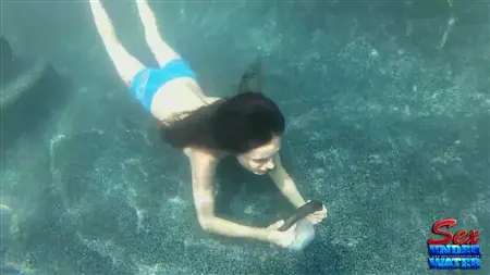 Menina sob água lambe um vibrador de borracha