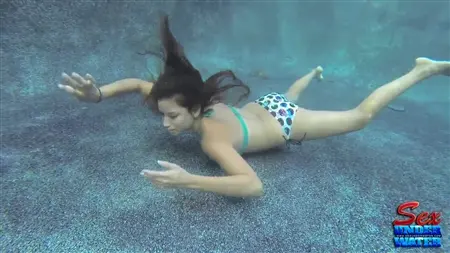 Uma garota esbelta tenta chupar um pau de borracha sob a água