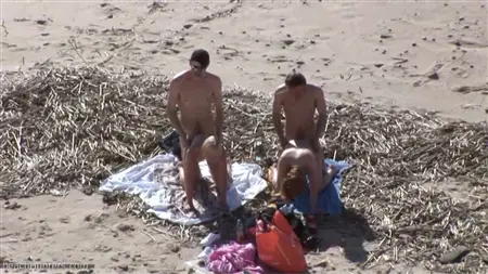 Uma multidão de caras na praia deixa um círculo de duas prostitutas